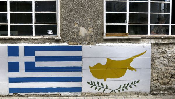 A representation of the Greek, left, and Cyprus flags are painted on a wall as a Greek Cypriot soldier is seen inside a guard post by the U.N controlled buffer zone as they cuts across the Cypriot divided capital Nicosia - Sputnik International