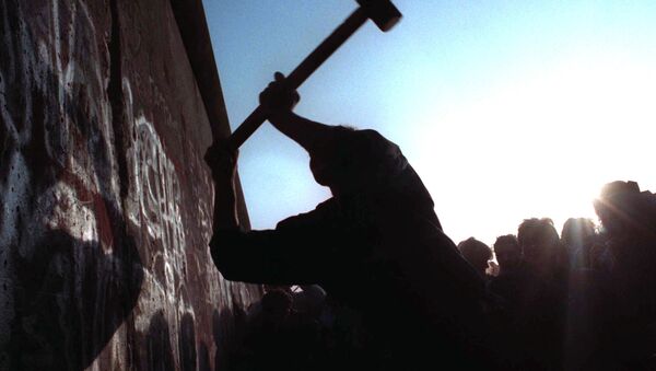 A man hammers away at the Berlin Wall on Nov. 12, 1989 as the border barrier between East and West Germany was torn down after 28 years, symbolically ending the Cold War. - Sputnik International