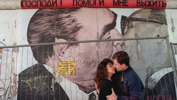 Two unidentified tourists kiss in front of a painting on one of the rare remaing parts of the Wall in Berlin, in October 1995 - Sputnik International