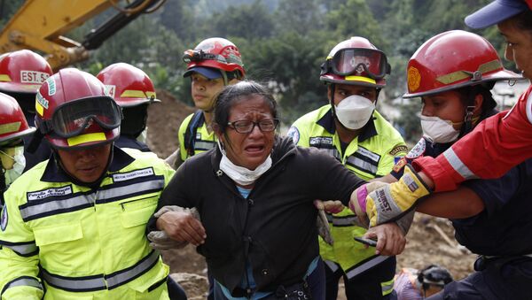Rescue workers help a woman after she identified two family members as their bodies are retrieved from the site of a mudslide in Cambray, a neighborhood in the suburb of Santa Catarina Pinula, on the outskirts of Guatemala City, Saturday, Oct. 3, 2015. - Sputnik International