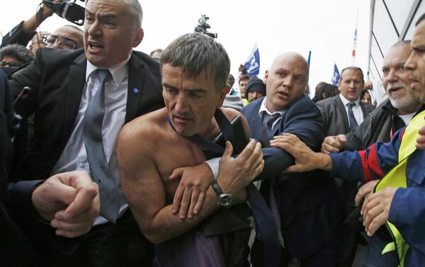 A shirtless Xavier Broseta (2ndL), Executive Vice President for Human Resources and Labour Relations at Air France, is evacuated by security after employees interrupted a meeting with representatives staff at the Air France headquarters building at the Charles de Gaulle International Airport in Roissy, near Paris, France, October 5, 2015. Air France confirmed in a meeting with staff on Monday that it plans to cut 2,900 jobs by 2017 and shed 14 aircraft from its long-haul fleet as part of efforts to lower costs, two union sources said. - Sputnik International