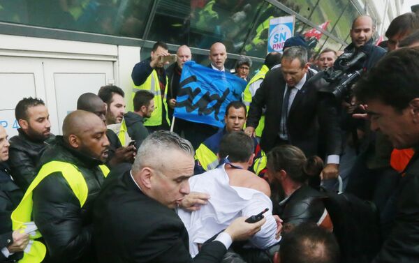 Air France director of Human Ressources, Xavier Broseta, center (back to the camera), protected by security guards tries to flee the Air France headquarters at Roissy Airport, north of Paris, France, during scuffles with union activists, Monday, Oct. 5, 2015. Union activists protesting proposed layoffs at Air France stormed the headquarters during a meeting about the job cuts, zeroing in on two managers who had their shirts torn from their bodies, scaled a fence and fled under police protection. - Sputnik International