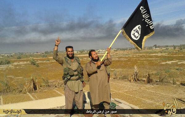 In this photo released on Sunday, June 28, 2015, by a website of Islamic State militants, an Islamic State militant waves his group's flag as he and another celebrate in Fallujah, Iraq, west of Baghdad In this photo released on Sunday, June 28, 2015, by a website of Islamic State militants, an Islamic State militant waves his group's flag as he and another celebrate in Fallujah, Iraq, west of Baghdad - Sputnik International