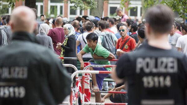 Police stand next to asylum seekers waiting in front of the reception center for refugees in Berlin, Germany, Friday, Aug. 7, 2015. - Sputnik International