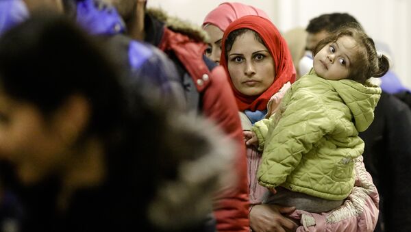 A migrant woman with a child stands in a queue of refugees and migrants after she arrived with a train at the train station Schoenefeld near, Berlin, Germany, Wednesday, Oct. 7, 2015. - Sputnik International