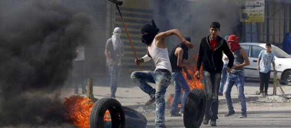 A Palestinian protester moves a burning tyre during clashes with the Israeli army at Qalandia checkpoint near occupied West Bank city of Ramallah October 6, 2015 A Palestinian protester moves a burning tyre during clashes with the Israeli army at Qalandia checkpoint near occupied West Bank city of Ramallah October 6, 2015 - Sputnik International