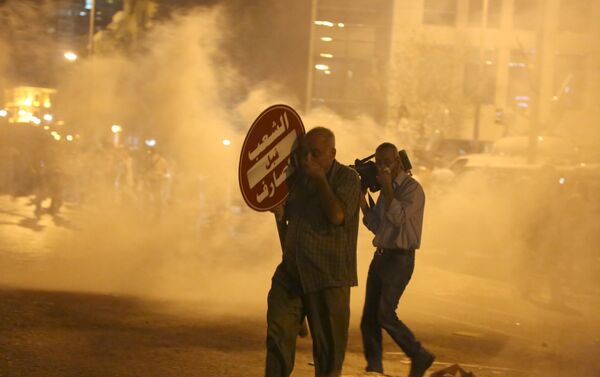 A protester and a cameraman (R) cover their faces as they are affected by tear gas fired by security forces in Martyr square, downtown Beirut, Lebanon October 8, 2015. Lebanese security forces fired tear gas and water cannons to break up an anti-government protest in Beirut on Thursday, and the country's fractious leaders postponed talks aimed at resolving a political crisis that is feeding public discontent. - Sputnik International