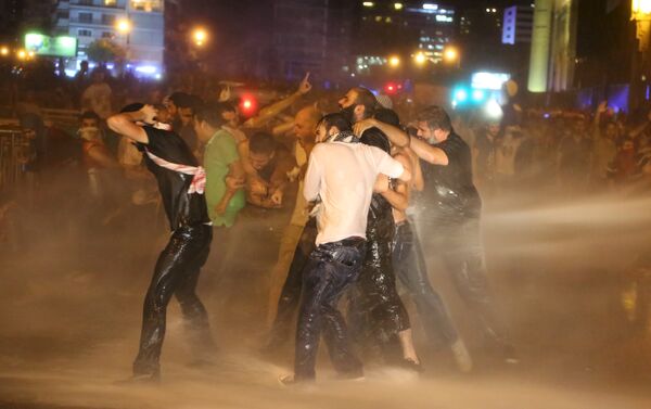 Protesters hold on to each other as they are sprayed with water from police water cannons in Martyr square, downtown Beirut, Lebanon October 8, 2015. Lebanese security forces fired tear gas and water cannons to break up an anti-government protest in Beirut on Thursday, and the country's fractious leaders postponed talks aimed at resolving a political crisis that is feeding public discontent. - Sputnik International