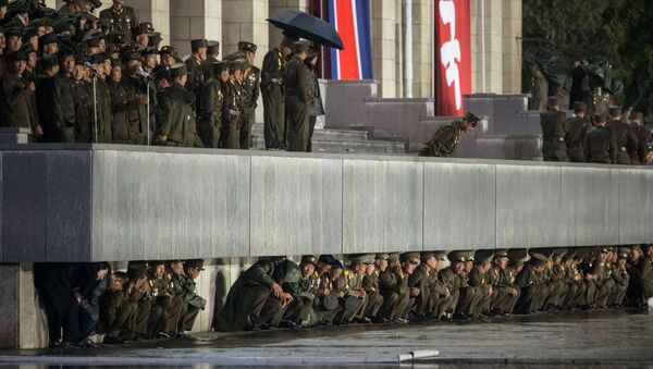 North Korean soldiers shelter from the rain beneath a balcony following a mass military parade in Pyongyang on October 10, 2015 - Sputnik International