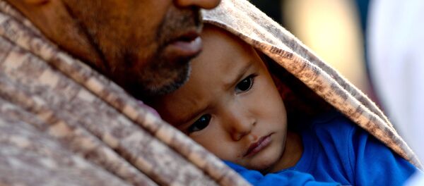 A migrant holds a child after their arrival at the railway station in Lehrte, near Hannover, northern Germany, Saturday, Oct. 3, 2015. - Sputnik International