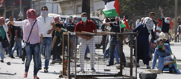 Palestinian protesters take up position during clashes with Israeli troops in the West Bank city of Hebron October 13, 2015 - Sputnik International