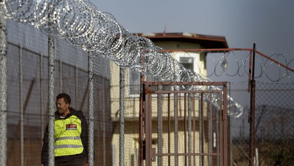 A security guard walks along a fence topped with barbed and razor wire in a facility for a detention of foreigners in the village of Drahonice, western Czech Republic, October 2, 2015 - Sputnik International