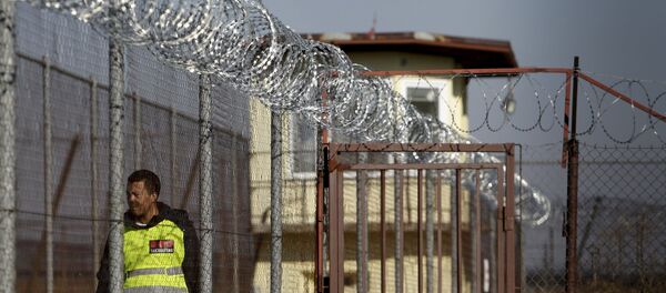 A security guard walks along a fence topped with barbed and razor wire in a facility for a detention of foreigners in the village of Drahonice, western Czech Republic, October 2, 2015. - Sputnik International