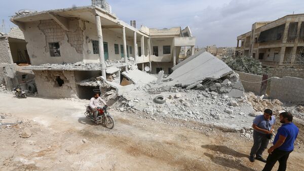 A man drives a motorcycle near a site hit by what residents said were airstrikes carried out by the Russian air force in the town of Darat Izza in Aleppo's countryside October 13, 2015 - Sputnik International