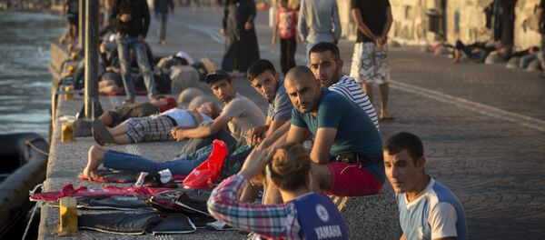 Migrants rest on an embankment of the port while waiting to be registered at the southeastern island of Kos, Greece, Wednesday, Aug. 19, 2015 Migrants rest on an embankment of the port while waiting to be registered at the southeastern island of Kos, Greece, Wednesday, Aug. 19, 2015 - Sputnik International