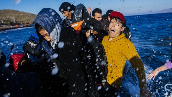 Refugees and migrants react as they arrive on a rubber boat on the Greek island of Lesbos, after crossing the Aegean sea from Turkey, on October 15, 2015. - Sputnik International