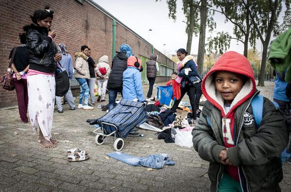 Refugees collect clothes, brought by residents of the neighborhood, outside the Schuttersveld Sports Centre designed as emergency shelter in Rotterdam, The Netherlands, on October 9, 2015 - Sputnik International