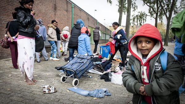 Refugees collect clothes, brought by residents of the neighborhood, outside the Schuttersveld Sports Centre designed as emergency shelter in Rotterdam, The Netherlands, on October 9, 2015 - Sputnik International