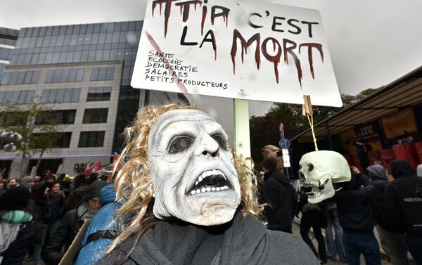 A protester with a mask demonstrates against the free trade agreement TTIP (Transatlantic Trade and Investment Partnership) during an EU summit in Brussels, Belgium on Thursday, Oct. 15, 2015. - Sputnik International