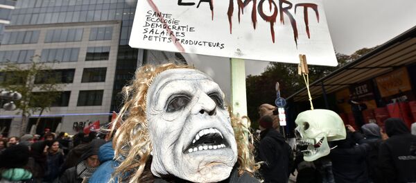 A protester with a mask demonstrates against the free trade agreement TTIP (Transatlantic Trade and Investment Partnership) during an EU summit in Brussels, Belgium on Thursday, Oct. 15, 2015. - Sputnik International