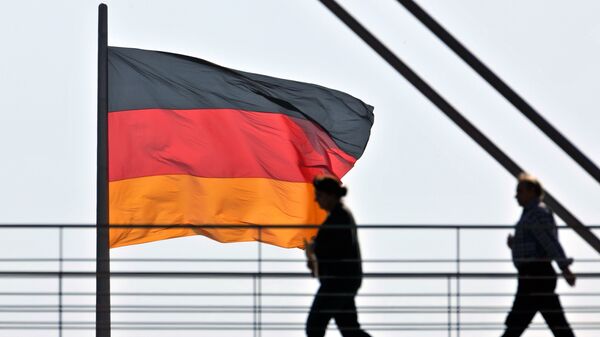People pass a giant German National flag on the Reichstag, which houses the German parliament Bundestag, as they cross a bridge between two office buildings on Thursday, April 2, 2009 in Berlin - Sputnik International