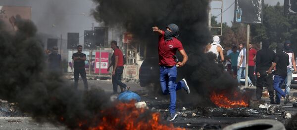 A Palestinian demonstrator hurls rocks towards Israeli border guards (unseen) during clashes at the Hawara checkpoint, south of the West Bank city of Nablus on October 16, 2015 - Sputnik International