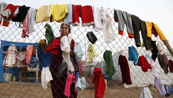 A Syrian refugee woman hangs laundry on a fence at an informal tented settlement in Irbil, northern Iraq. - Sputnik International