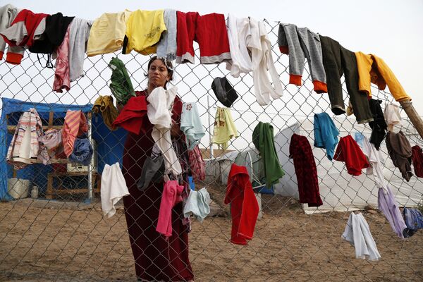 A Syrian refugee woman hangs laundry on a fence at an informal tented settlement in Irbil, northern Iraq. A Syrian refugee woman hangs laundry on a fence at an informal tented settlement in Irbil, northern Iraq. - Sputnik International