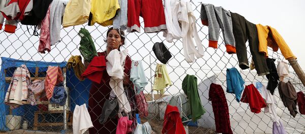 A Syrian refugee woman hangs laundry on a fence at an informal tented settlement in Irbil, northern Iraq. A Syrian refugee woman hangs laundry on a fence at an informal tented settlement in Irbil, northern Iraq. - Sputnik International
