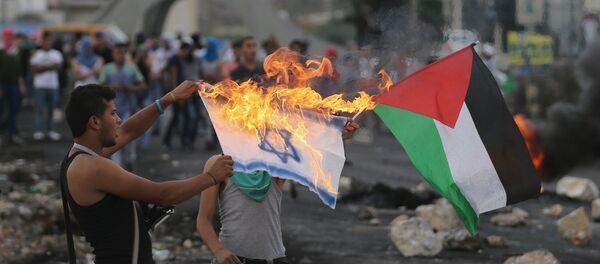 A Palestinian protester burns a replica Israeli flag as another holds a Palestinian flag during clashes with the Israeli troops near the Jewish settlement of Bet El, near the West Bank city of Ramallah October 18, 2015 A Palestinian protester burns a replica Israeli flag as another holds a Palestinian flag during clashes with the Israeli troops near the Jewish settlement of Bet El, near the West Bank city of Ramallah October 18, 2015 - Sputnik International