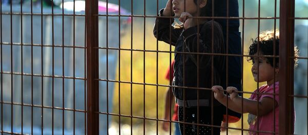 Children wait behind a fence to pass with their families in the southern Macedonian town of Gevgelija, Friday, Sept. 11, 2015. - Sputnik International