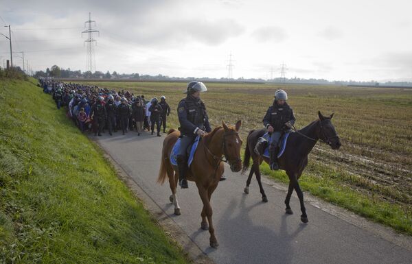 Policemen ride on their horses in front of migrants after they crossed from Croatia, in Dobova, near a border crossing between Croatia and Slovenia Tuesday, Oct. 20, 2015. Policemen ride on their horses in front of migrants after they crossed from Croatia, in Dobova, near a border crossing between Croatia and Slovenia Tuesday, Oct. 20, 2015. - Sputnik International