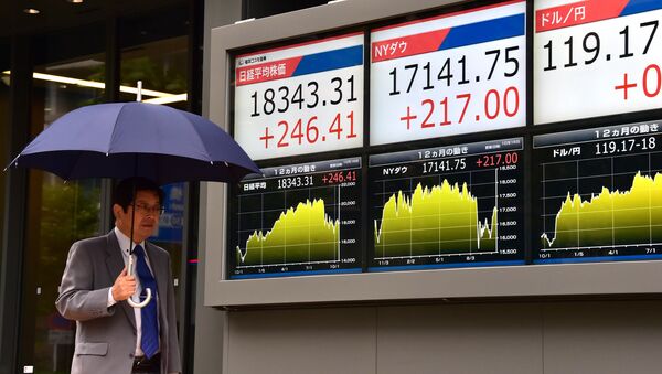 A businessman passes before a share prices board in Tokyo on October 16, 2015 - Sputnik International