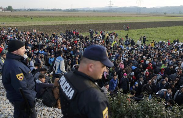 Slovenian police officers watch as migrants walk from Dobova towards a transit camp in Brezice, Slovenia October 21, 2015 - Sputnik International
