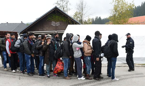 German police officer instructs migrants ahead of their walk from the Austrian-German border to a first registration point of the German federal police in the small Bavarian village Wegscheid, southern Germany, on October 20, 2015 German police officer instructs migrants ahead of their walk from the Austrian-German border to a first registration point of the German federal police in the small Bavarian village Wegscheid, southern Germany, on October 20, 2015 - Sputnik International