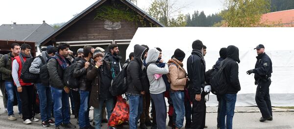 German police officer instructs migrants ahead of their walk from the Austrian-German border to a first registration point of the German federal police in the small Bavarian village Wegscheid, southern Germany, on October 20, 2015 - Sputnik International