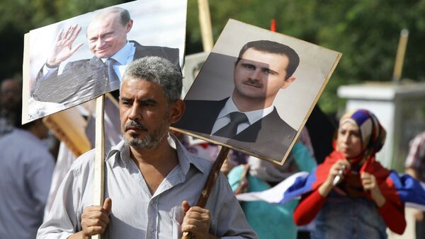 A Syrian man holding up portraits of President Bashar al-Assad and his Russian counterpart Valdimir Putin (L) joins several hundred people who gathered near the Russian embassy in Damascus on October 13, 2015 - Sputnik International