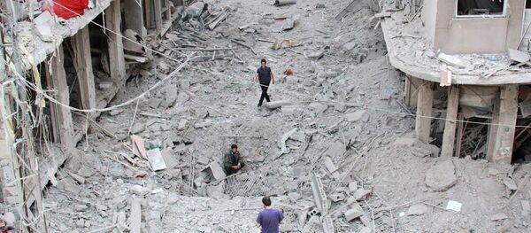 People walk on the rubble of damaged buildings after Syrian military helicopter allegedly droped barrel bombs over the city of Daraya, southwest of the capital Damascus - Sputnik International