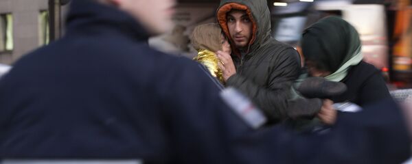 Members of a Syrian family stand in a street as migrants and refugees are evicted by French police from a camp at the Porte de Saint-Ouen in Paris early on October 2, 2015 - Sputnik International