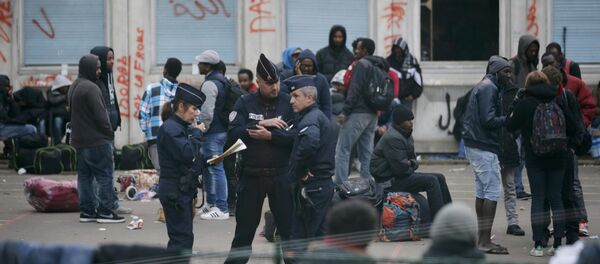 French police stand near migrants who gather in the courtyard of the Lycee Jean Quarre, an empty secondary school occuiped by hundred of migrants and asylum seekers in the 19th district in Paris, France, October 23, 2015 French police stand near migrants who gather in the courtyard of the Lycee Jean Quarre, an empty secondary school occuiped by hundred of migrants and asylum seekers in the 19th district in Paris, France, October 23, 2015 - Sputnik International