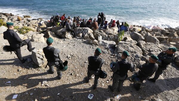 Migrants wait on the rocks on the shoreline under the surveillance of policemen on September 30, 2015 at the French-Italian border in Ventimiglia - Sputnik International