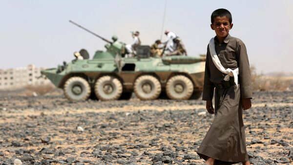 A boy walks in front of fighters of the Popular Resistance Committees riding on an armored vehicle during a ceremony where they formally take over territory that the government had managed to recover from Houthi militants, in the central province of Marib October 11, 2015. - Sputnik International