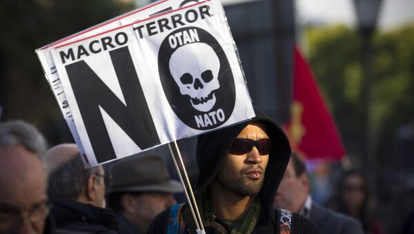 A protester holds a sign that reads Macro terror, no to NATO during a demonstration against NATO in Lisbon, on Saturday, Nov. 20, 2010 - Sputnik International