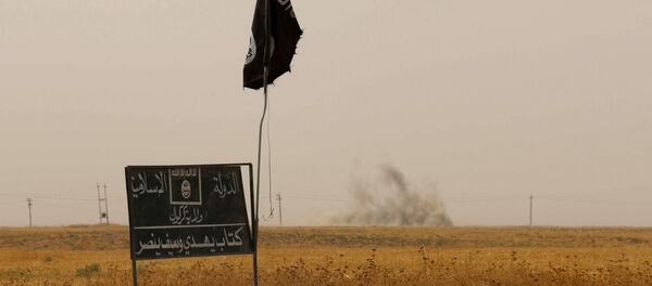 (FILES) A file picture taken on September 11, 2015, shows smoke rising in the distance behind an Islamic State (IS) group flag and banner after Iraqi Kurdish Peshmerga fighters reportedly captured several villages from IS group jihadists in the district of Daquq, south of the northern Iraqi multi-ethnic city of Kirkuk - Sputnik International