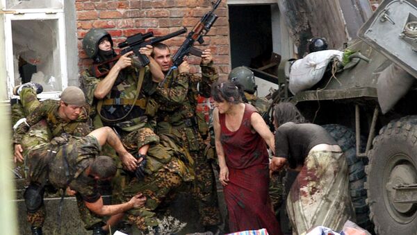 A Russian special police soldier (L) carries an injured colleague as two soldiers and two women take cover behind the APC during the rescue operation of Beslan's school, northern Ossetia, September 3,2004 - Sputnik International