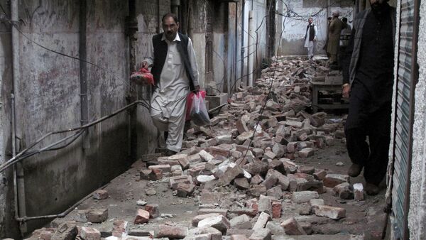 A man with his belongings walks past the rubble of a house after it was damaged by an earthquake in Mingora, Swat, Pakistan - Sputnik International