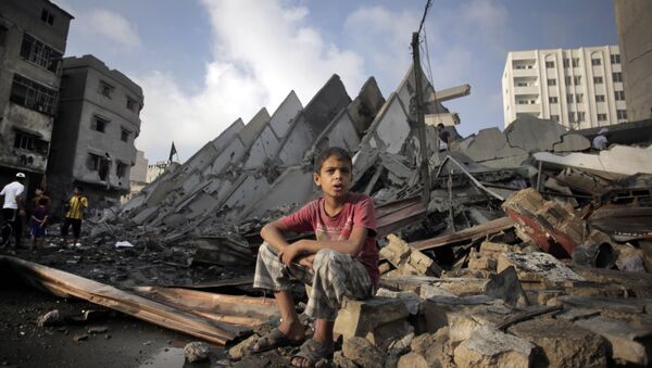 A Palestinian boy sits next to the destroyed 15-story Basha Tower following early morning Israeli airstrikes in Gaza City, Tuesday, Aug. 26, 2014. - Sputnik International