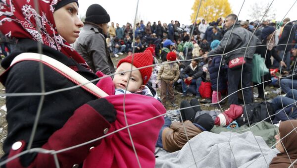 A woman holds a baby as migrants queue to cross the border into Spielfeld in Austria from the village of Sentilj, Slovenia, October 28, 2015. - Sputnik International