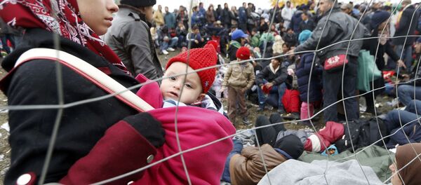 A woman holds a baby as migrants queue to cross the border into Spielfeld in Austria from the village of Sentilj, Slovenia, October 28, 2015. A woman holds a baby as migrants queue to cross the border into Spielfeld in Austria from the village of Sentilj, Slovenia, October 28, 2015. - Sputnik International