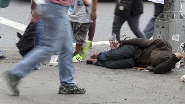 People walk past a homeless man asking for money on 14th Street, Friday, Sept. 4, 2015, in New York - Sputnik International